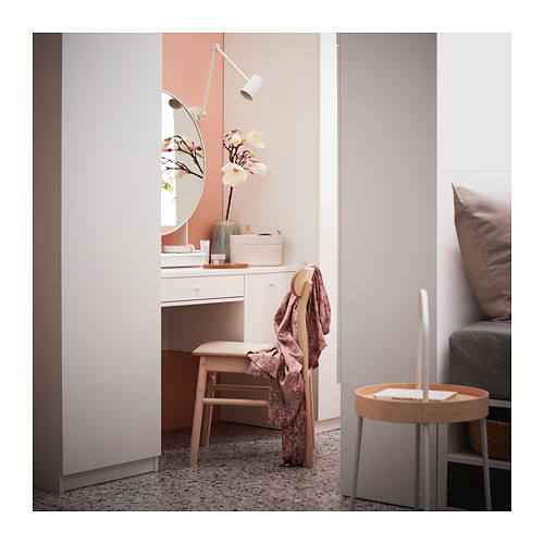 Un tocador blanco estrecho con tapa de cristal y silla de madera junto a una cama en un dormitorio.