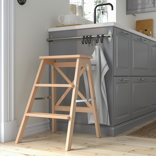 Escalera de tijera de madera BEKVÄM contra isla de cocina gris. Plegable, de haya ligera con tres peldaños.