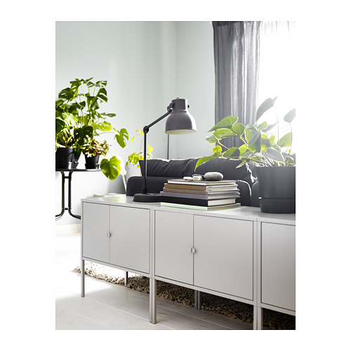 Sala de estar moderna con gabinete LIXHULT blanco, lámpara gris y plantas. Diseño limpio y minimalista.