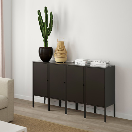 Aparador negro de 4 puertas, cactus, cesta, libros. Entre el sillón y la pared.