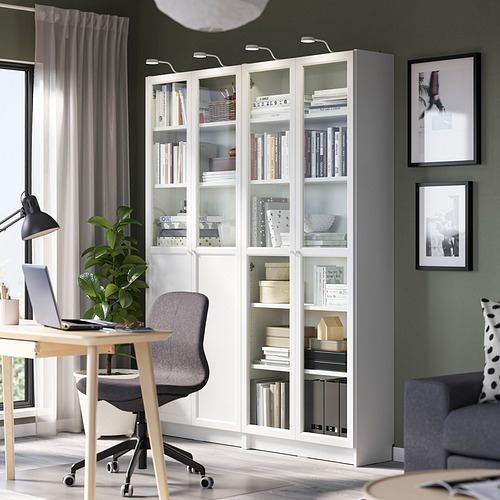 Estantería blanca BILLY con libros, junto a escritorio con silla, lámpara y portátil.