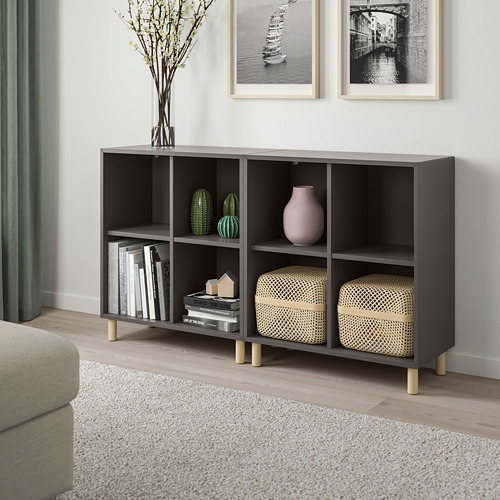 A modern living room with an EKET black storage unit, books, decor, and a beige sofa.