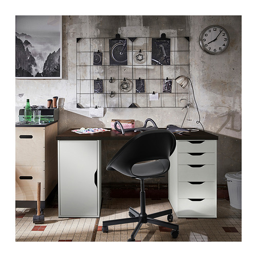 Configuración de oficina en casa con escritorio LAGKAPTEN en negro-marrón, almacenamiento blanco y silla negra, contra una pared con una pantalla de imágenes de cuadrícula y un reloj.