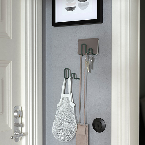 Ganchos de pared que sostienen llaves, bolso y billetera junto a la puerta.