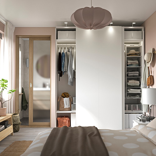 Dormitorio moderno con armario PAX, paredes rosas, cama de lunares, lámpara, planta.