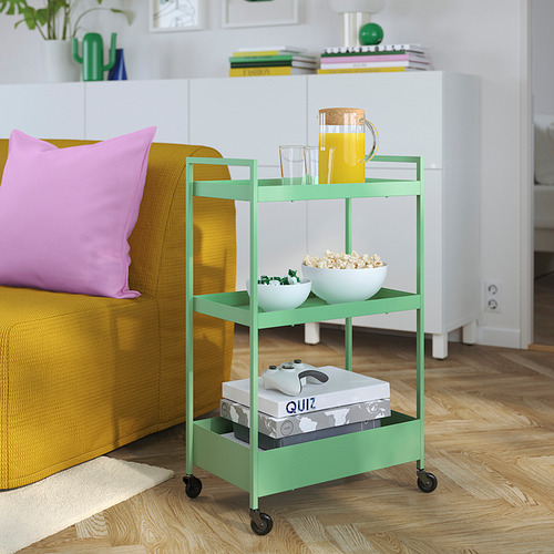 Carro verde NISSAFORS debajo del sofá, con jugo, palomitas de maíz, controlador de juegos y juegos de mesa.