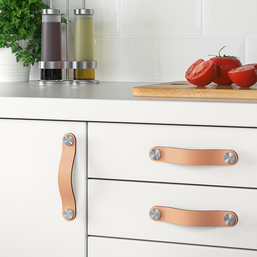 Cajones de cocina modernos con manijas de cuero y accesorios, que incluyen condimentos y tomates en rodajas.