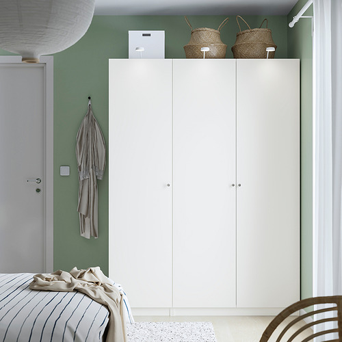 White ikea PAX wardrobe beside door, three sections, woven baskets, striped towel, bed with striped duvet.
