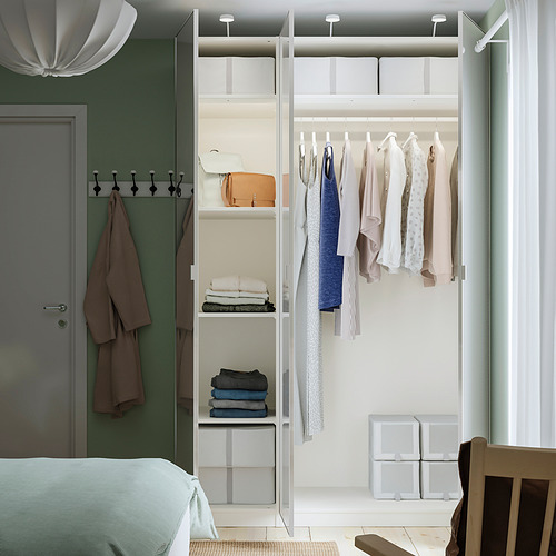 Dormitorio moderno con armario PAX; ropa colgada, suéteres doblados y toallas, además de contenedores de almacenamiento.