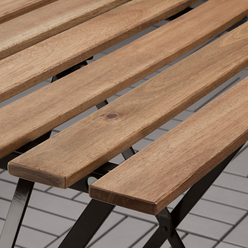 Mesa de exterior plegable de madera con patas de metal negro, que muestra una superficie lisa y acabada y una construcción robusta.