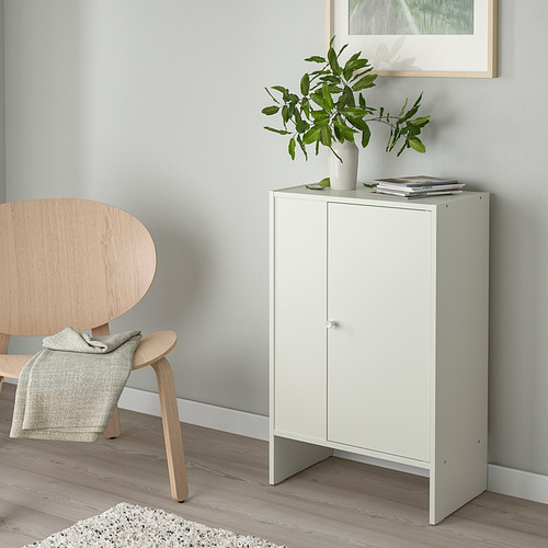 Armario de almacenamiento blanco con revistas y plantas. Silla de madera con manta, decoración minimalista.