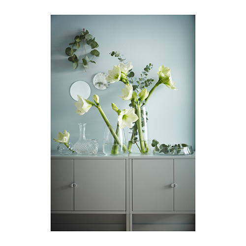 Flores blancas en jarrones transparentes sobre un armario de almacenamiento gris.
