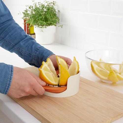 Una persona corta una naranja con un cortador UPPFYLLD sobre una tabla de madera.