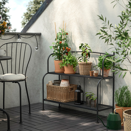 Black LÄCKÖ plant shelf holds potted herbs & plants, fits balcony with chair.