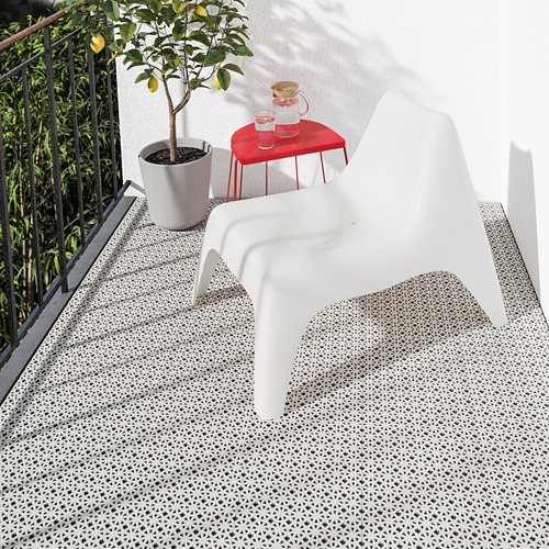 Pequeño balcón blanco de ALTAPPEN con un patrón geométrico, que encaja perfectamente debajo de una silla, junto a un limonero y una mesa roja.
