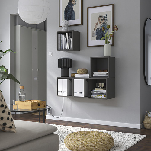 Sala de estar moderna con sofá blanco, mesa de café, planta y unidades de almacenamiento EKET llenas de libros y decoración.