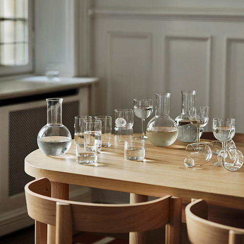 Jarra STOCKHOLM 2025 sobre mesa de madera con recipientes de vidrio