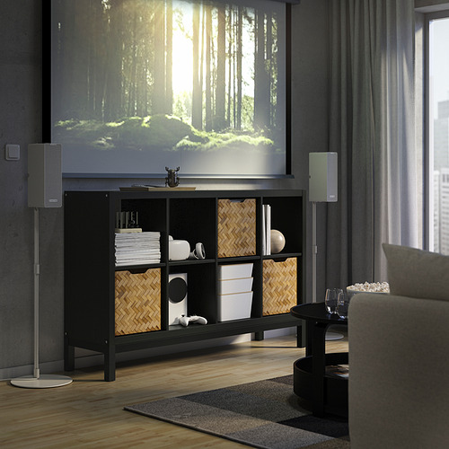 Sala de estar moderna con aparador KALLAX, parlantes grises, bosque proyectado, sofá acogedor, piso de madera y cortinas.