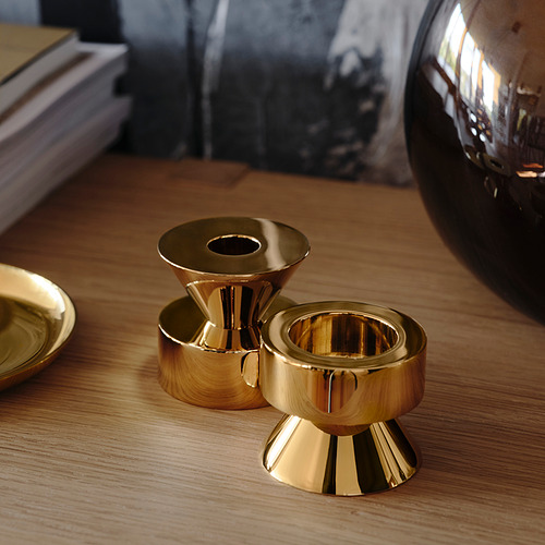 Tres candelabros de oro, dos de pie, uno acostado, de metal pulido sobre mesa de madera.