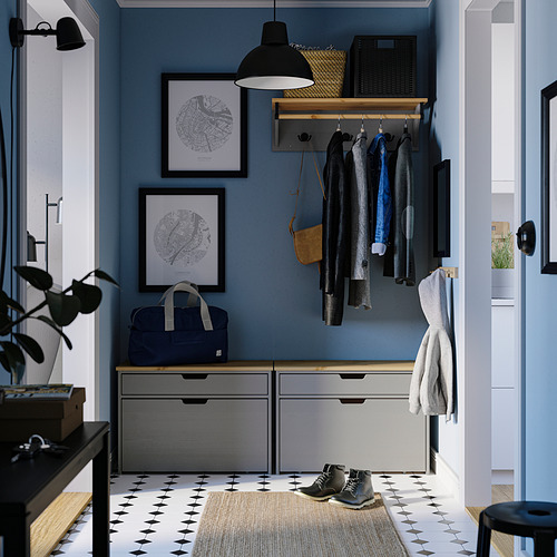 Moderno pasillo azul con banco de almacenamiento gris KALLSÖ, abrigos colgantes y arte de pared. El banco se adapta a espacios estrechos, con cajones para el almacenamiento.