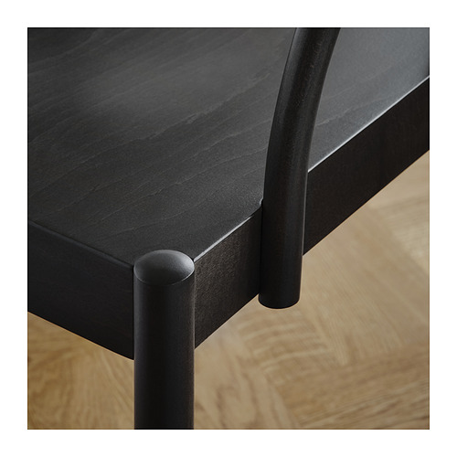Primer plano de una moderna mesa de comedor negra con elegantes patas de metal curvadas y un acabado liso en la mesa.