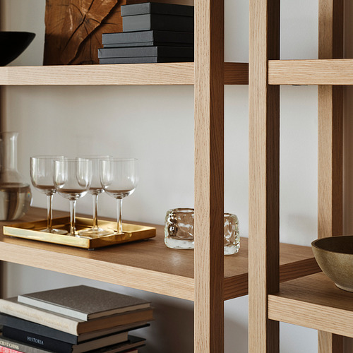 Estantes de madera que sostienen copas de vino, libros y artículos decorativos, fijados de forma segura a la pared.