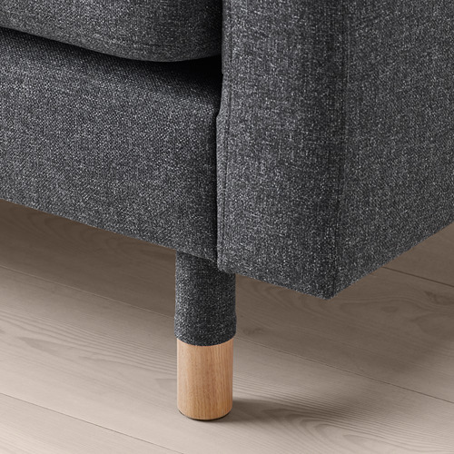 Primer plano de un elegante sofá de tela oscura con robustas patas de madera, que muestra un diseño de calidad y comodidad.