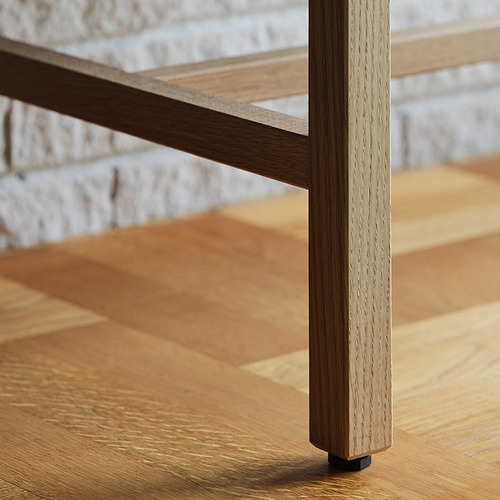 Primer plano de la robusta pata de la mesa de madera, que muestra una textura de grano fino y un acabado natural.