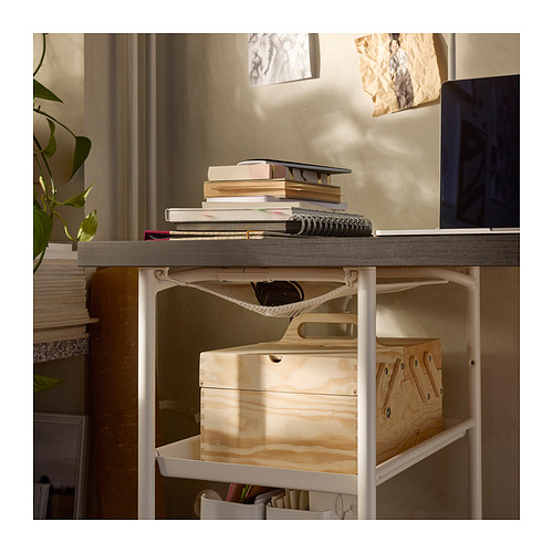 A LAGKAPTEN desk with a grey top and white legs, holding books, a laptop, and storage boxes.