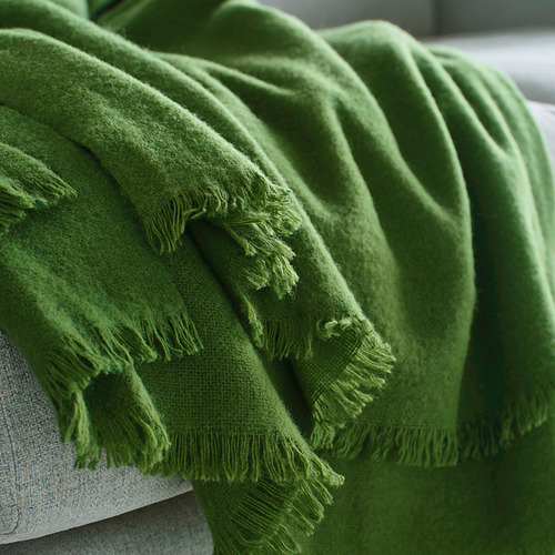 Manta tejida a mano de color verde brillante con flecos drapeados suavemente, con una suave textura de lana merino.