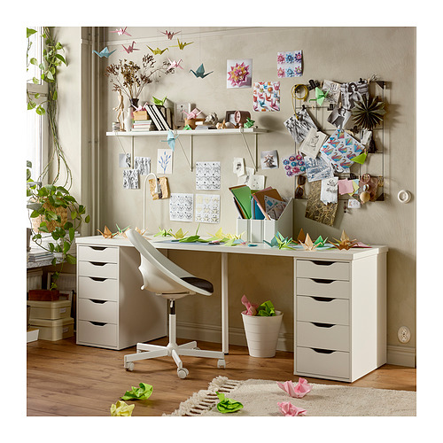 Espacio de trabajo creativo: escritorio blanco LAGKAPTEN con cajones, silla, pared decorada, plantas, origami y manualidades.