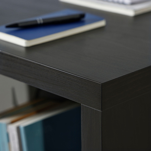 Escritorio negro con superficie lisa, que muestra artesanía de calidad. Cerca de allí, un bolígrafo descansa sobre un cuaderno azul, enfatizando un espacio de trabajo ordenado y organizado.