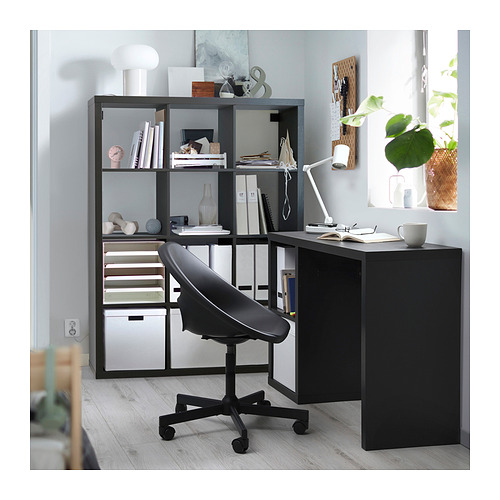 Montaje de escritorio negro con estantería KALLAX, plantas, libros y lámpara.