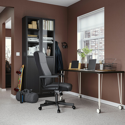 Configuración de oficina en casa con escritorio LAGKAPTEN negro, silla ergonómica, estantería y computadora portátil.