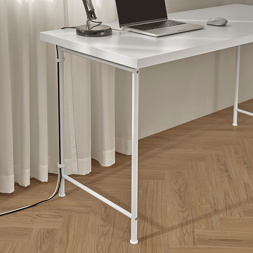 Escritorio blanco con computadora portátil, mouse y lámpara. Patas ajustables para pisos irregulares, se muestra manejo de cables.