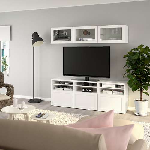 Sala de estar moderna con TV de pantalla plana, estantes, armarios, lámpara, silla de mimbre, mesa de centro, planta.