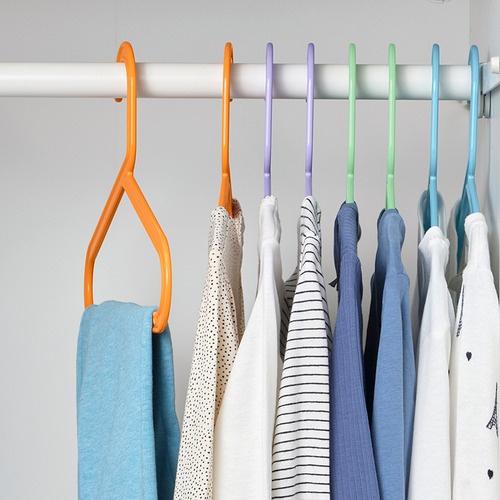 Armario con perchas de colores que sujetan ropa; Perchas naranjas, moradas, verdes y azules que organizan cuidadosamente las prendas.