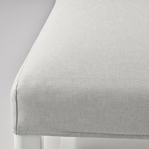 Primer plano de la silla tapizada en tela gris claro de líneas limpias, que luce su tejido texturizado y su cómodo cojín.