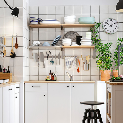 Cocina moderna con encimeras de madera, armarios blancos, portacuchillos magnético, plantas, taburete, reloj.
