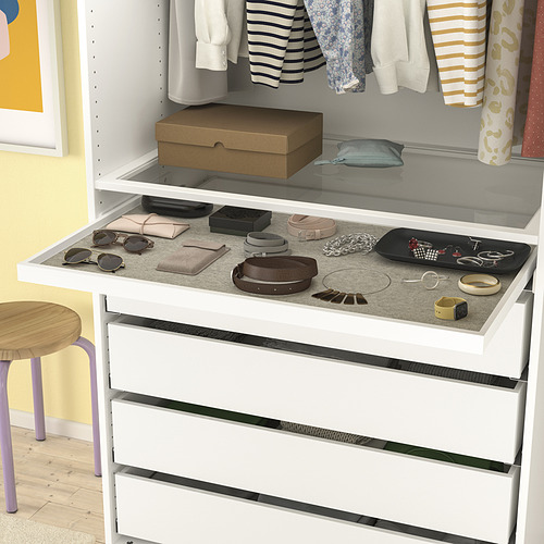 Cómoda blanca con bandeja de fieltro gris que muestra accesorios. La bandeja se extrae para facilitar el acceso.