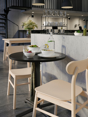 Cafetería moderna con mesa redonda STENSELE negra, cuencos blancos, sillas de madera clara, vasos colgantes y una decoración elegante.