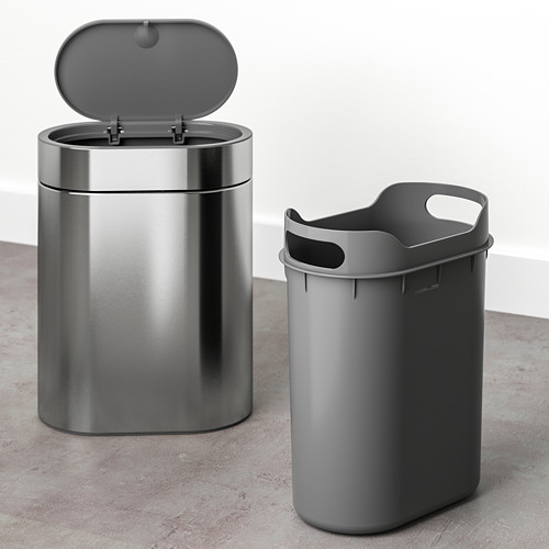 Dos cubos de basura, uno de acero inoxidable con tapa abierta, otro gris con asa, adecuados para espacios estrechos, diseñados para facilitar la limpieza y la fijación de las bolsas de residuos.