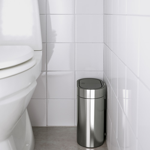 Baño moderno con inodoro blanco y bote de basura delgado de acero inoxidable, tapa a prueba de huellas dactilares y apertura con sensor.