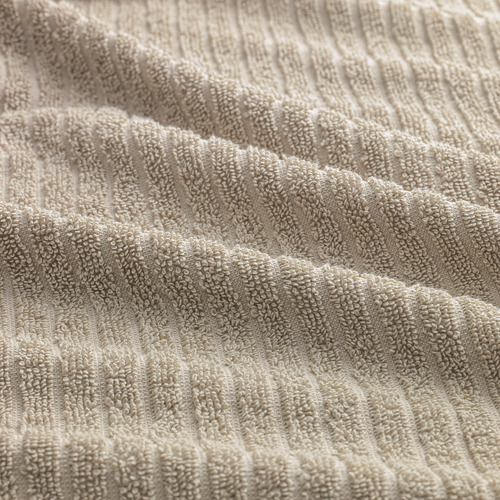 Primer plano de una toalla beige suave y texturizada, que muestra su tejido lujoso y absorbente.