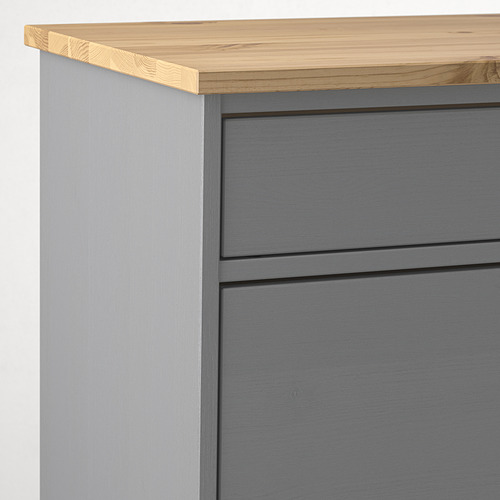 Banco de madera KALLSÖ en primer plano. Construcción de pino macizo, encimera de madera natural lisa, cajones pintados en gris con elegantes tiradores integrados.