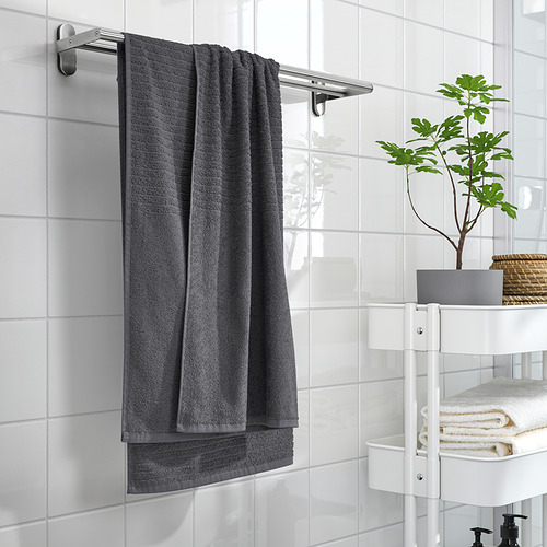 Toalla VÅGSJÖN gris en la barra del baño alicatado, con estante de sostenedor de plantas y toallas.