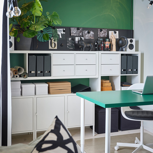 Moderna oficina verde con almacenamiento blanco, escritorio, planta y pizarra.