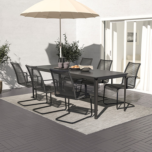 Patio moderno con mesa, 6 sillas de mimbre y sombrilla en la terraza de azulejos. A la sombra, ideal para cenar.