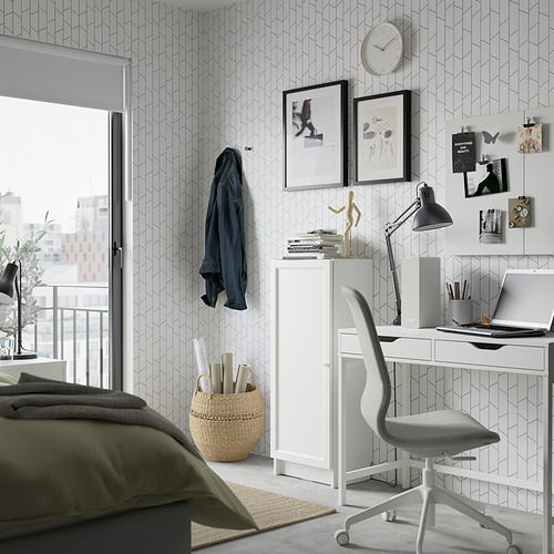 Dormitorio moderno con papel pintado geométrico, una estantería blanca BILLY, una silla de oficina gris y un escritorio con una computadora portátil y una lámpara.