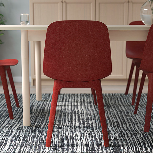 Una silla de madera roja con un diseño elegante se sienta junto a una mesa blanca, fácil de montar con un clic.